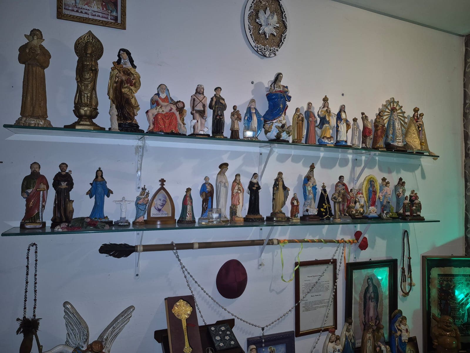 Estantes com estatuetas de santos e divindades de diversas religiões